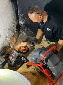 Tech using drain scope in basement
